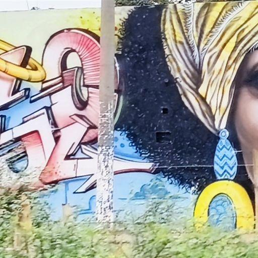Buntes Graffiti mit dynamischem Schriftzug und eindringlichem Frauenporträt mit Turban.